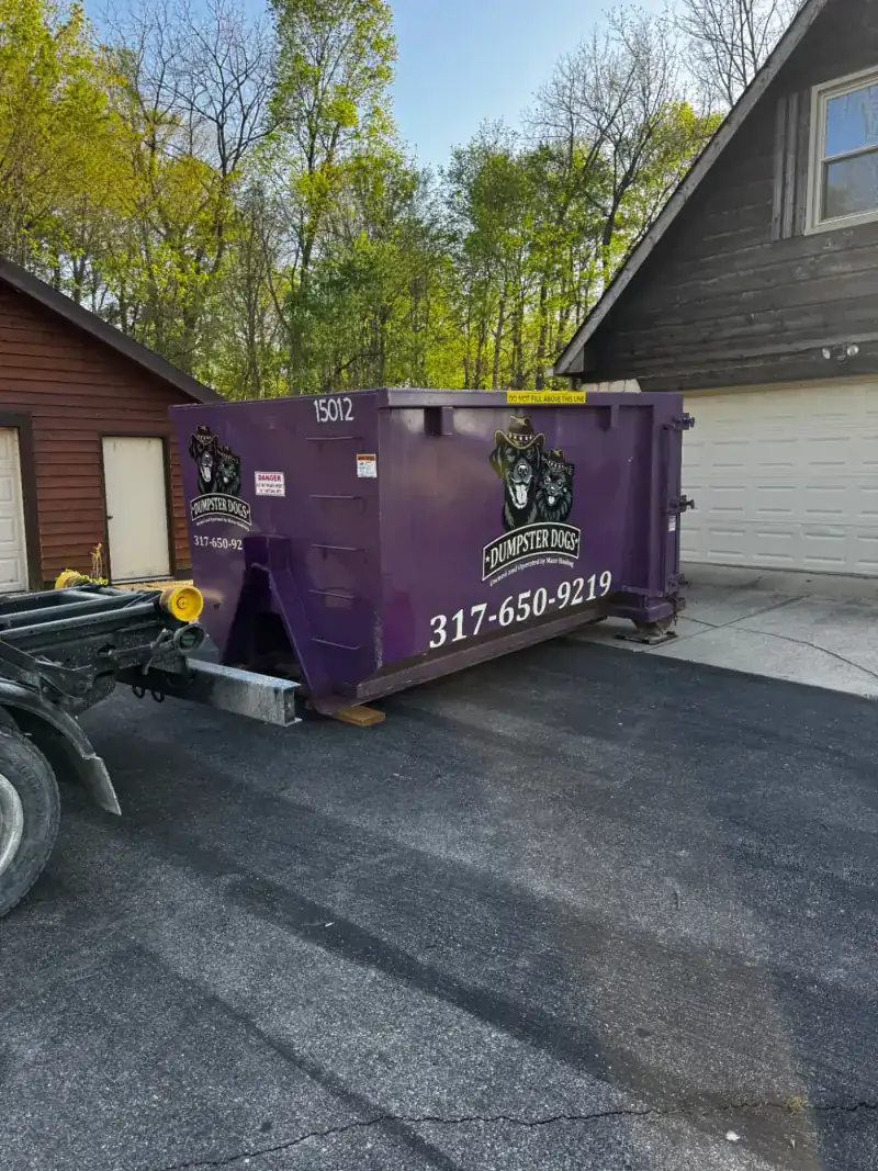 Dumpster Dogs truck setting down a 16-yard dumpster on a driveway